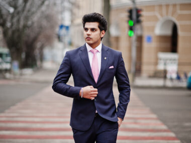 elegant indian macho man model suit pink tie walking cross pedestrian
