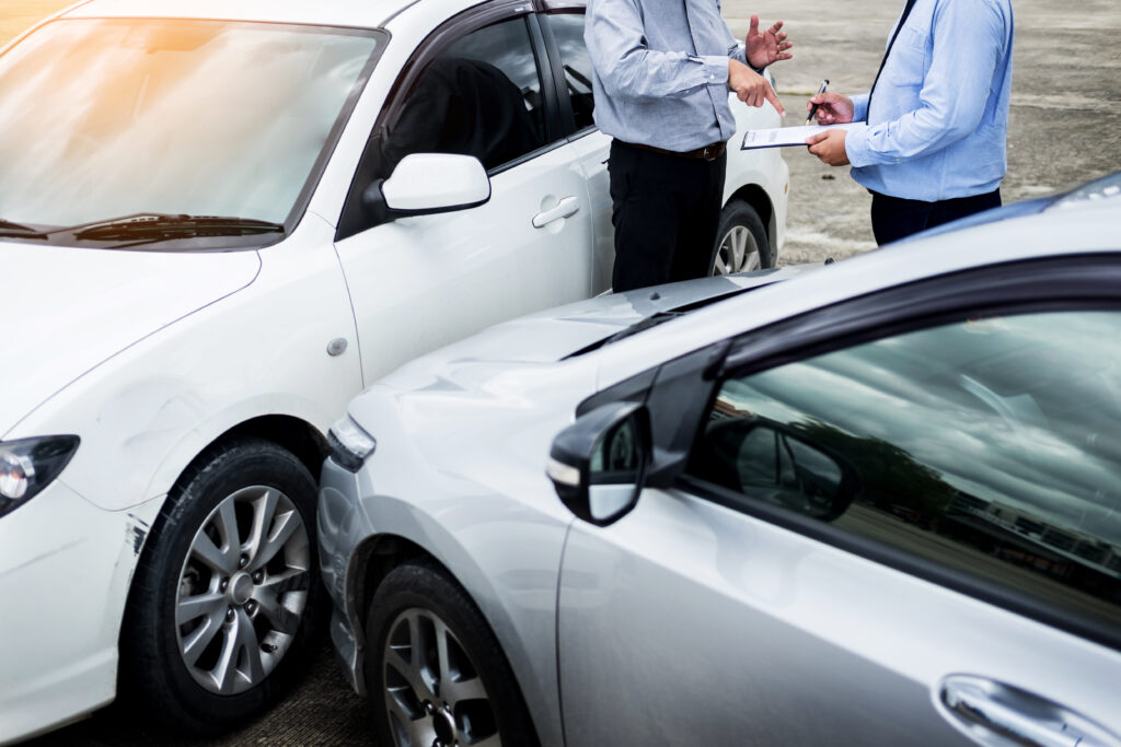 insurance agent writing clipboard while examining car after accident.Auto Accident Lawyer