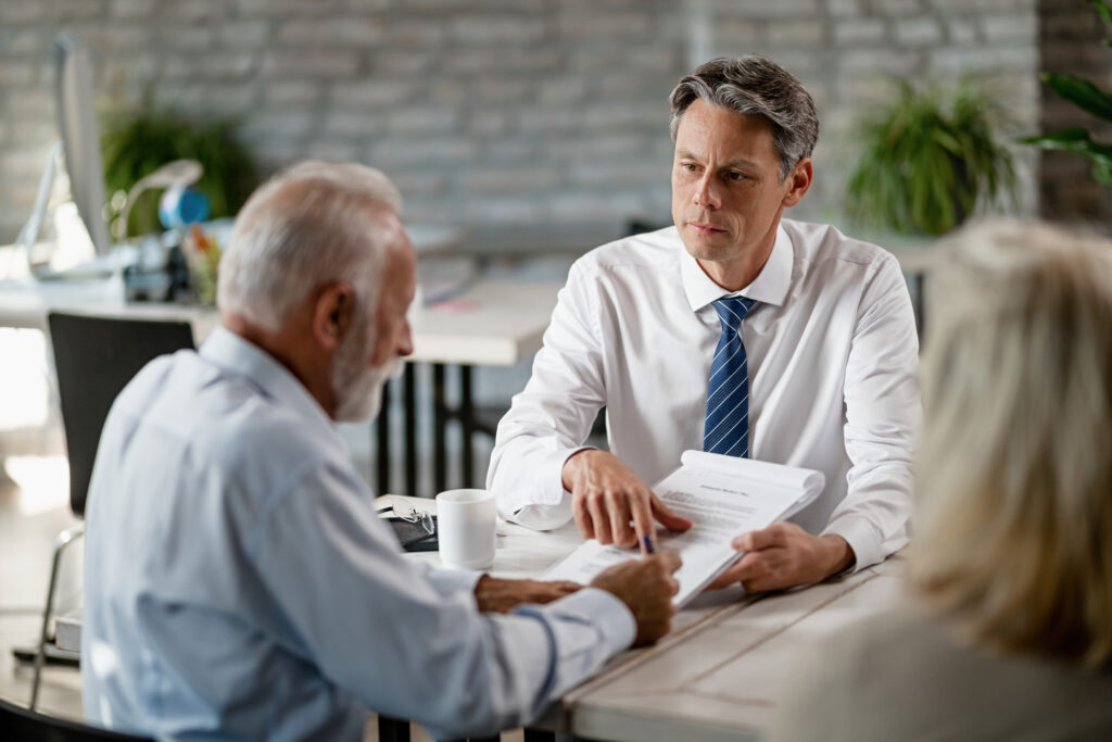 insurance agent having meeting with senior clients pointing place signature contract