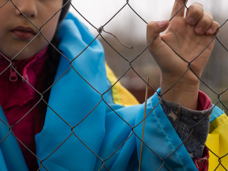 sad little girl with flag ukraine metal fence social problem refugees forced migrants