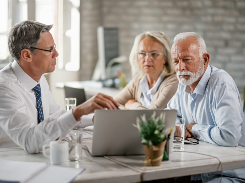 mature couple their bank manager using computer while having consultations office